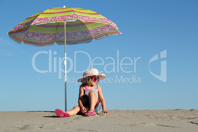 little girl with sunglasses sitting under sunshade