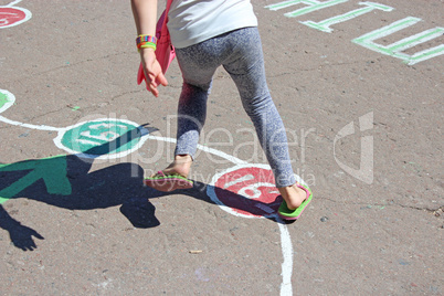 girl runs on the childish drawings on the asphalt