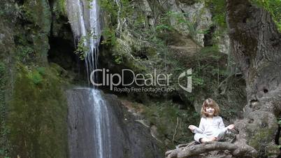 little girl meditate by the waterfall