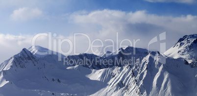 Panoramic view on snowy mountains in clouds