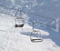 Two chair-lift with snowdrift and off-piste slope in sun morning