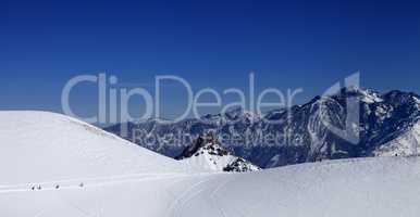 Snowboarders move on footpath to off piste slope at sun day