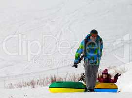 Father and daughter with snow tube at sun day