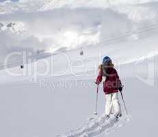 Girl on skis in off-piste slope with new fallen snow at sun day