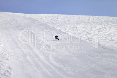 Ski slope and snowboarder at sun day