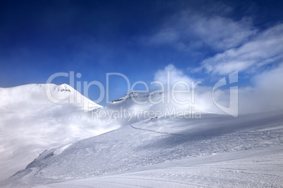 Ski slope with snowmobile trail and mountains in mist at nice da