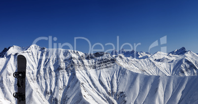 Panoramic view on snowy mountains and snowboard