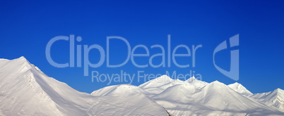 Panoramic view of snowy mountains and blue clear sky