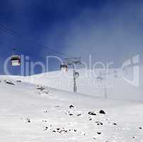 Gondola lifts and ski slope in mist