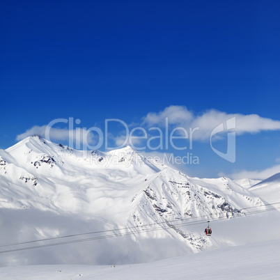 Winter snowy mountains and ski slope at nice day.