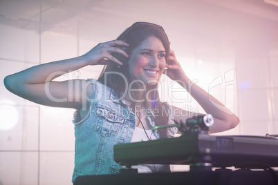 Pretty female DJ listening to the headphone while playing music