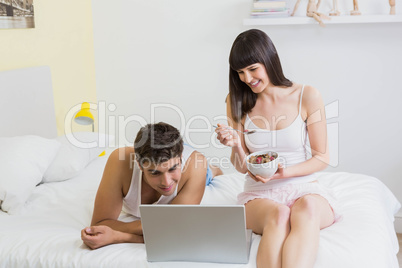 Young couple looking at laptop on bed