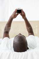 Man text messaging on mobile phone in bedroom