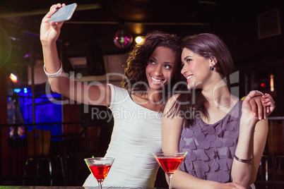 Young women taking a selfie while having a cocktail drink