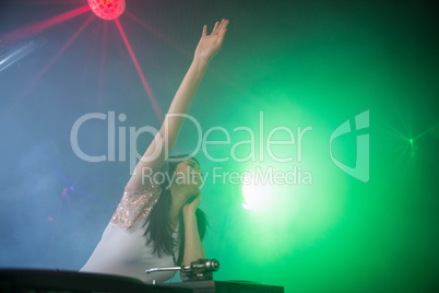 Pretty female DJ waving her hand while playing music