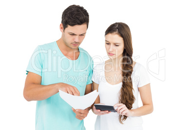 Young couple using calculator for paying bills