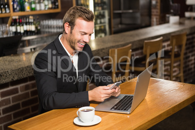 Thoughtful man using laptop and smartphone