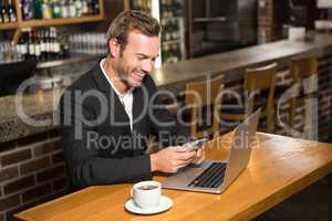 Thoughtful man using laptop and smartphone