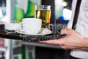 Waiter serving whiskey and a cup of coffee