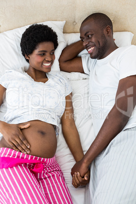 Pregnant couple relaxing on bed