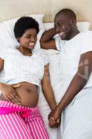 Pregnant couple relaxing on bed