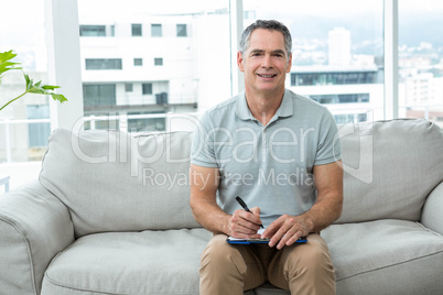 Man sitting on sofa and writing on notepad