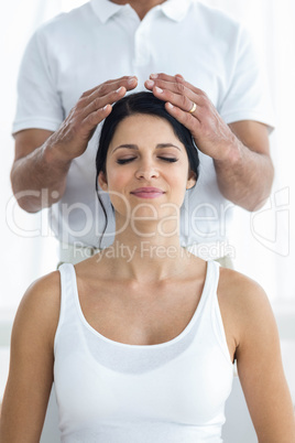 Pregnant woman receiving a head massage from masseur