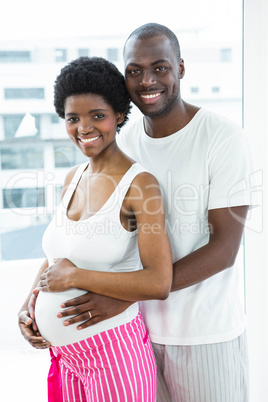 Pregnant couple embracing in bedroom