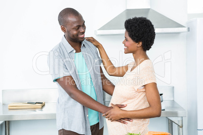 Pregnant couple cuddling in kitchen