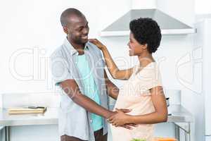 Pregnant couple cuddling in kitchen