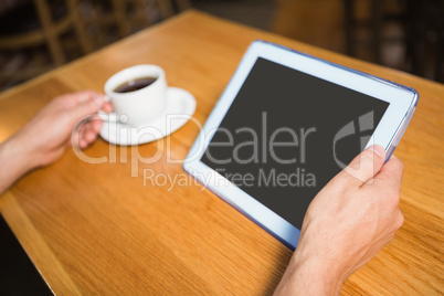 Masculine hands holding tablet and coffee