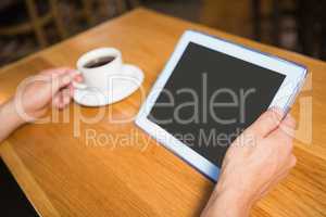 Masculine hands holding tablet and coffee