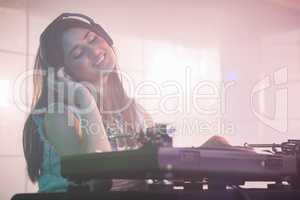 Pretty female DJ listening to the headphone while playing music