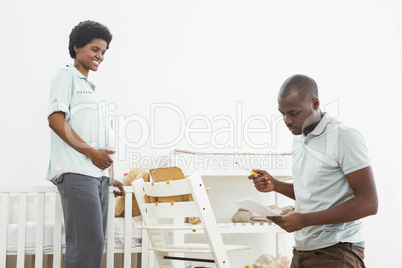 Pregnant woman looking at man reading a list while fixing a baby