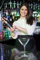 Pretty bartender mixing a cocktail drink in cocktail shaker