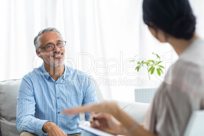 Female doctor writing on clipboard while consulting a man