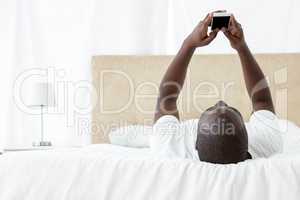 Man text messaging on mobile phone in bedroom