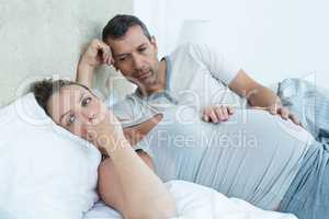 Expecting couple lying on bed and chatting