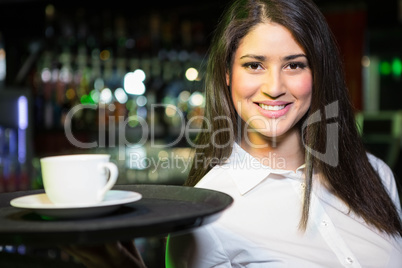 Portrait of pretty waitress serving a cup of coffee