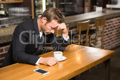 Handsome man looking at smartphone and having a coffee