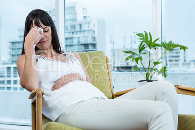 Pregnant woman sitting with headache