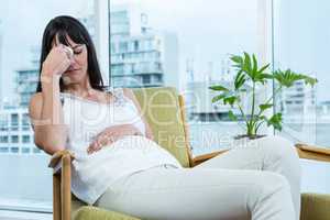 Pregnant woman sitting with headache