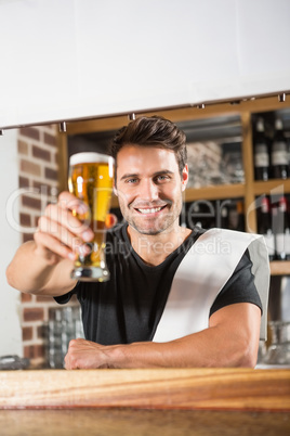 Handsome barman holding a pint of beer