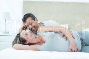 Expecting couple lying on bed and chatting