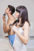 Young man shaving and young woman  straightening hair