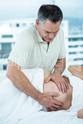 Pregnant woman receiving a stomach massage from masseur