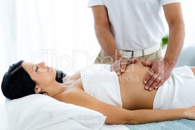 Pregnant woman receiving a stomach massage from masseur