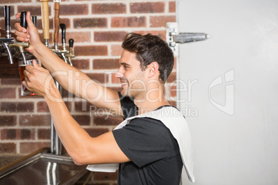 Handsome barman pouring a pint of beer