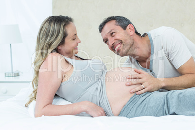 Expecting couple lying on bed and chatting