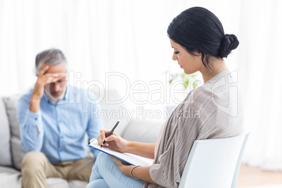 Female doctor writing on clipboard while consulting a man